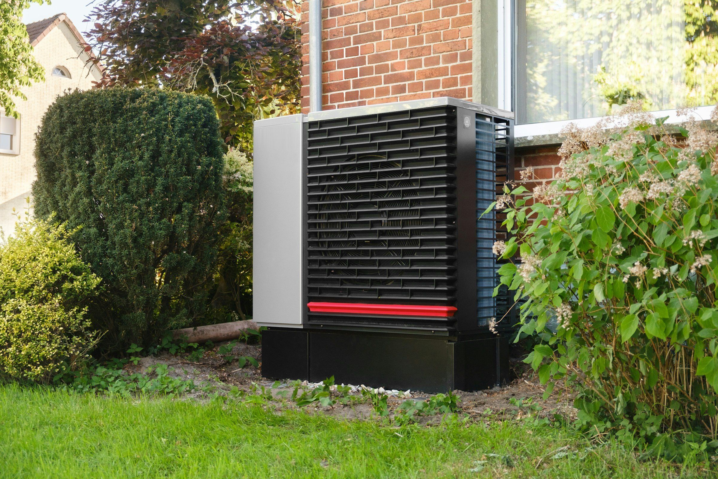 Wärmepumpe im Garten neben einem Haus